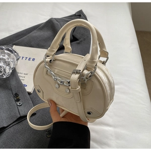 Detail of a creamy white mini leather handbag with silver chains and biker style studs