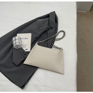 Detail der beigen gesteppten Tragetasche mit Kettenriemen und eleganter Trapezform