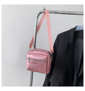 Detalle de mini bolso bandolera rosa metalizado con doble cremallera y correa de nylon