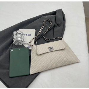 Detailansicht der beigen Umschlag-Schultertasche mit Webstruktur und Kette auf grauem Blazer
