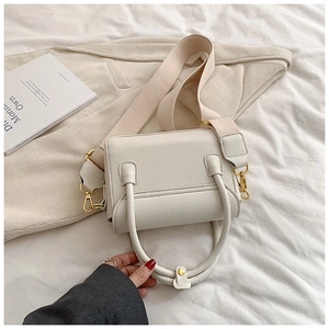 Détail du sac à main en cuir beige avec bandoulière rose et crochets dorés
