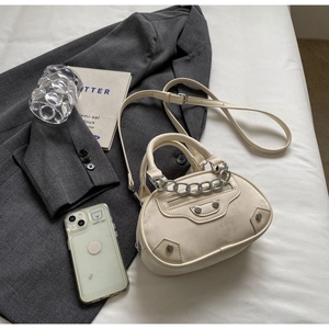 Detailed close-up of beige crossbody bag with silver chain and metal stud accents