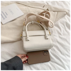 Gros plan d'un sac à main blanc en cuir grainé avec poignée nouée et bandoulière