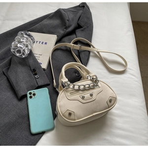 Detail of cream mini handbag with silver chain, metallic studs, and elegant top handle