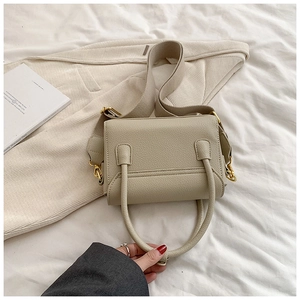Détail de la texture en cuir grainé beige et des finitions dorées de ce sac à main