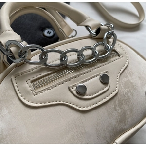 Detail shot of beige mini handbag with silver chain, rivets and textured faux leather