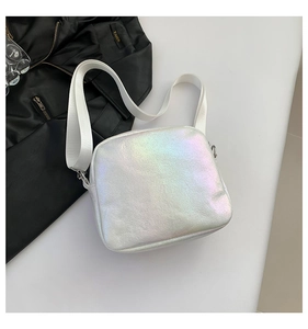 Detalle de bolso bandolera plateado holográfico con correa ancha de nailon y cremallera