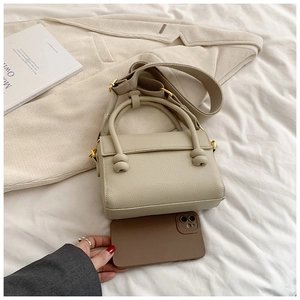 Détail d'un sac bandoulière en cuir beige avec nœuds et bandoulière réglable