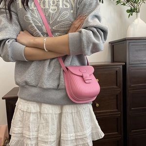 Pink pleated crossbody mini square bag with leather strap worn by model in casual style