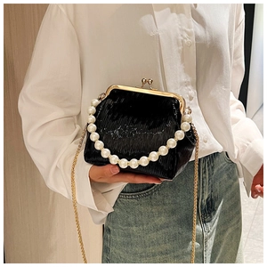 Detail view of black pleated kiss-lock bag with pearl handle and gold chain strap