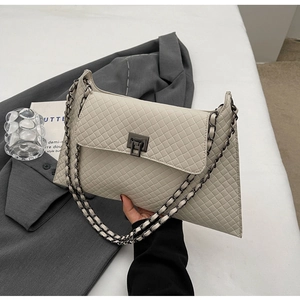Detail der cremeweißen Stepptasche mit Kettenriemen und dunklem Metalldrehverschluss