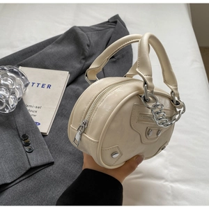 Close-up of beige leather mini handbag with metallic studs and silver chain handle