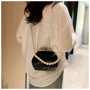 Detail view of mini black embossed clutch bag with pearl handle and gold chain strap