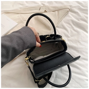 Vue de dessus de l'intérieur du sac en cuir litchi noir avec compartiment et boucle dorée