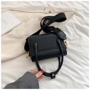 Détail du sac à main en cuir grainé noir avec boucle dorée et large bandoulière