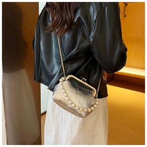 Detail view of silver pleated shell bag with pearl handle and metal kiss-lock closure