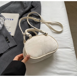 Detail showing the soft suede texture and silver hardware of the beige oval handbag
