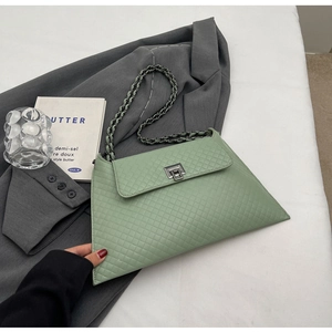 Detailansicht hellgrüne Stepptasche mit silberner Kette und Drehverschluss auf einem Blazer
