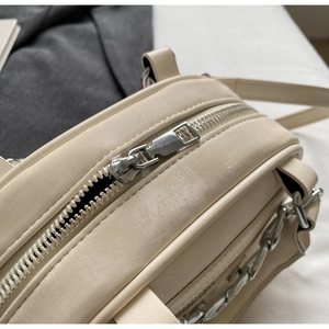 Detail of premium cream leather handbag featuring silver metal zipper and sleek finish