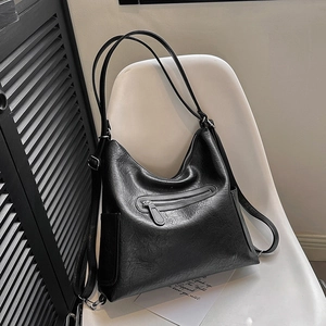 Borsa tote in morbida pelle nera con trama vintage cerata su una sedia bianca