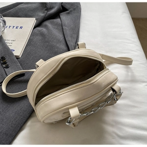 Top view of round beige crossbody bag showing interior lining and silver chain detail