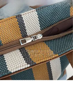 Detail shot of smooth silver metal zipper and woven striped fabric texture on tote bag