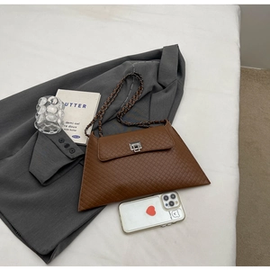 Detail der braunen gesteppten Kunstledertasche mit silberner Schnalle auf grauem Blazer