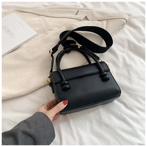 Détail du sac à main noir en cuir grainé avec finitions dorées et large bandoulière