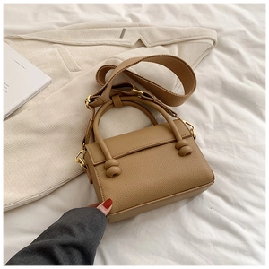 Détail du mini sac kaki en cuir texturé avec dorures et large bandoulière en tissu