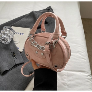 Detail view of pink round crossbody bag featuring silver hardware and mini buckle straps
