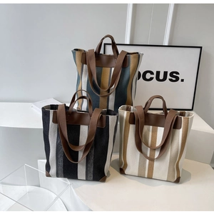 Detail view of striped canvas tote bags with leather corners and dual straps