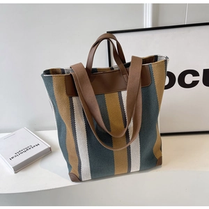 Detail of striped canvas tote with brown leather handles and reinforced corner protection
