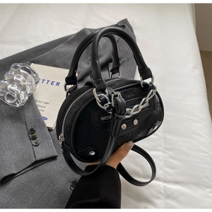 Macro shot of stylish black crossbody round bag with silver studs and chain detailing