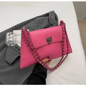 Detail einer fuchsia gesteppten Handtasche mit eleganter Metallkette und Drehverschluss