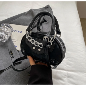 Close-up of black retro handbag with silver studs and chain detailing in street style