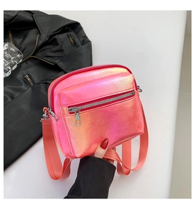 Primer plano detallado de un bolso bandolera rosa iridiscente con cremalleras plateadas