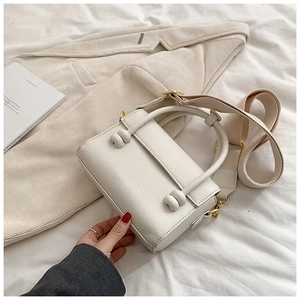 Détail du sac blanc en cuir grainé avec boucle à nœud et large bandoulière tissée