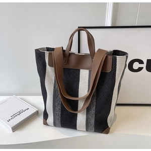 Detail of striped canvas tote bag showing reinforced leather corners and dual straps