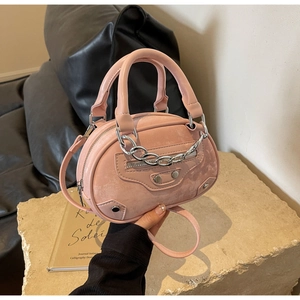 Detailed close-up of pink textured leather bag with metallic studs and chain hardware