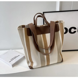 Detail view of striped canvas tote bag showing high-quality leather handles and brown trim