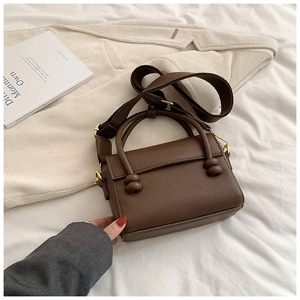 Détail d'un sac à main marron en cuir grainé avec poignée nouée et boucles en métal doré
