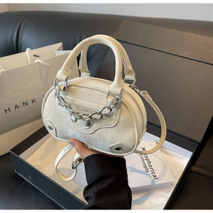 Detail of off-white leather round handbag featuring silver chain and metal rivets