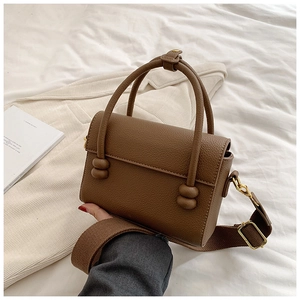 Gros plan d'un sac en cuir grainé marron avec détails dorés et large bandoulière