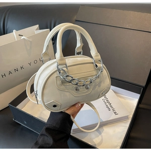 Detailed macro view of cream faux leather mini round bag with silver studs and hardware