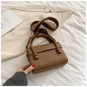 Vue détaillée du sac à main marron à motif litchi avec large bandoulière en tissu