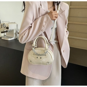 Fashionable off-white half-moon bag with silver studs and chain on a stylish model