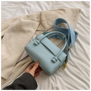 Détail du sac à main bleu clair en cuir avec nœuds décoratifs et bandoulière large