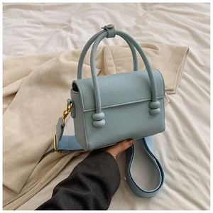 Vue détaillée du sac à main en cuir bleu clair avec bandoulière large en tissu tisse
