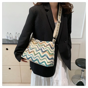 Détail du sac seau en laine bohème avec motifs ondulés et large bandoulière brodée élégante