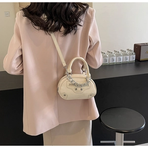 Model view of an off-white mini crossbody bag with silver chains and pink suit